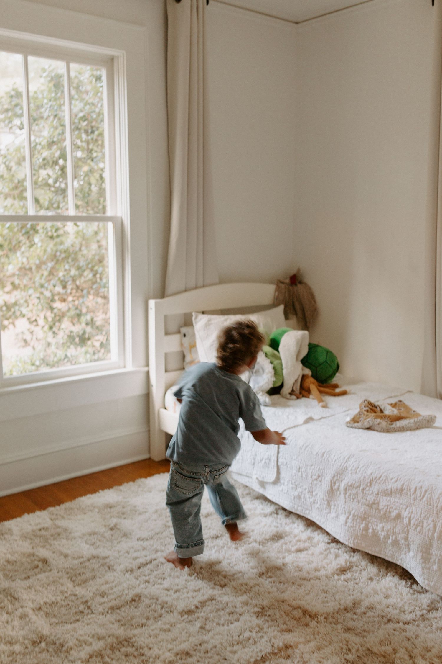 Active play session captured in a bright bedroom with hardwood floors and white decor.