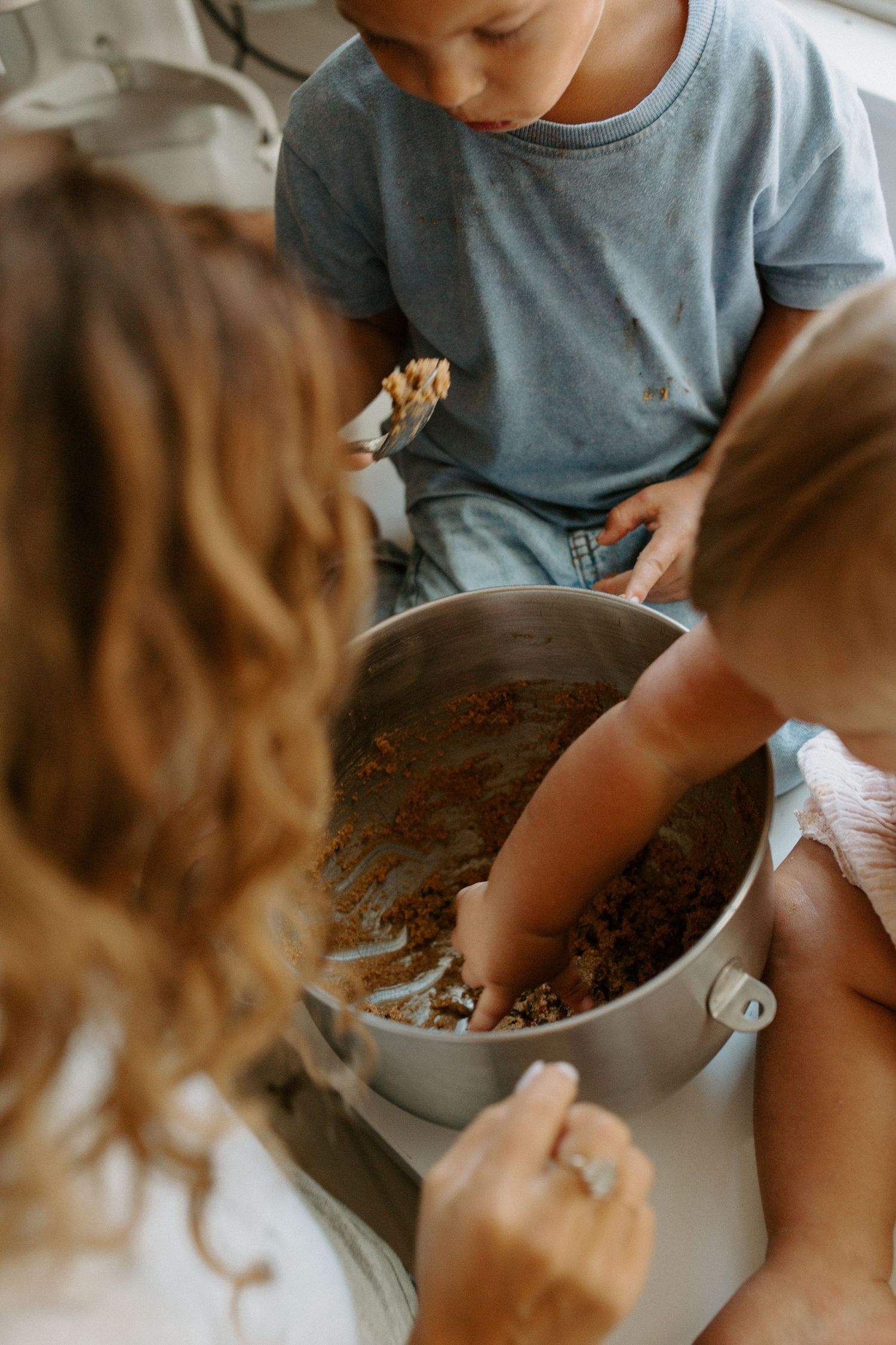 Child in blue shirt mixing ingredients in a large bowl while baking.