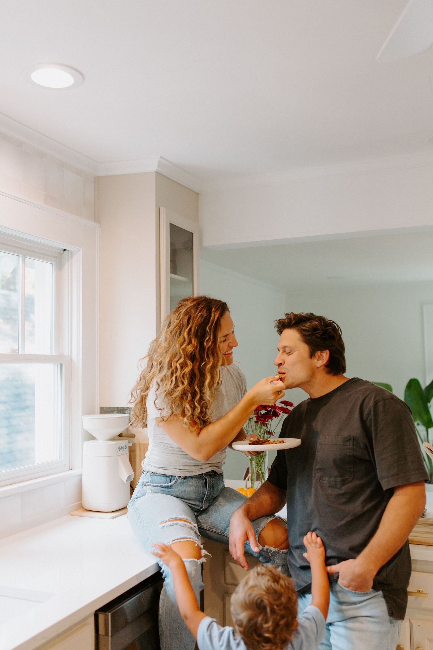 A playful moment between a couple in a bright modern kitchen with white cabinets.