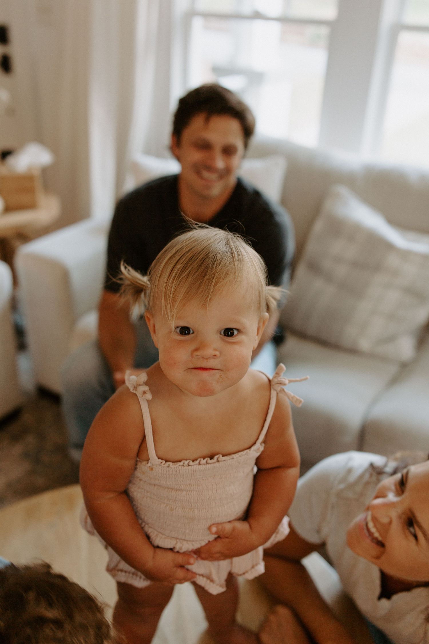 Sweet indoor portrait session showing joyful expressions in a bright living room setting.