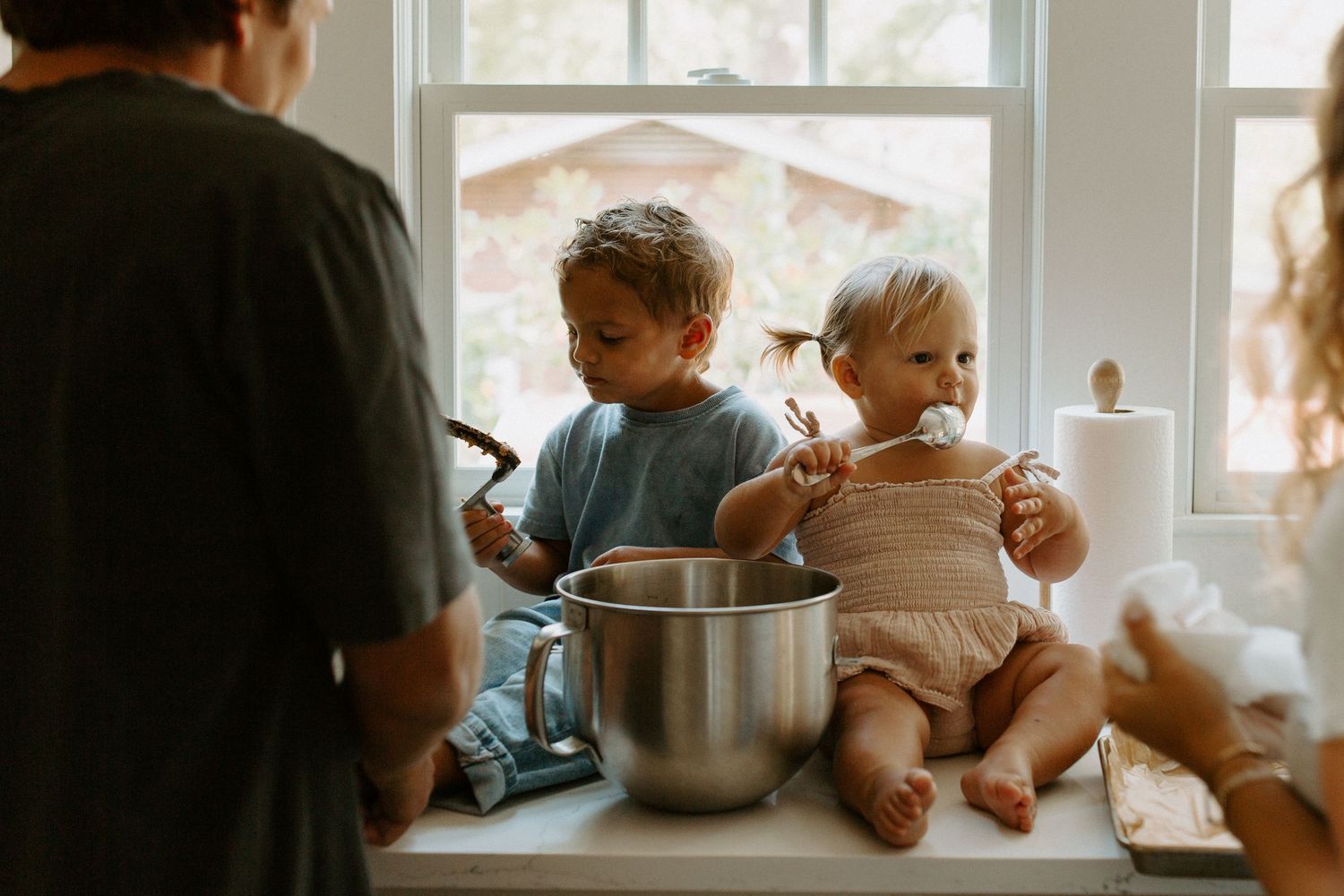 Children sitting by window sill in cozy indoor setting.