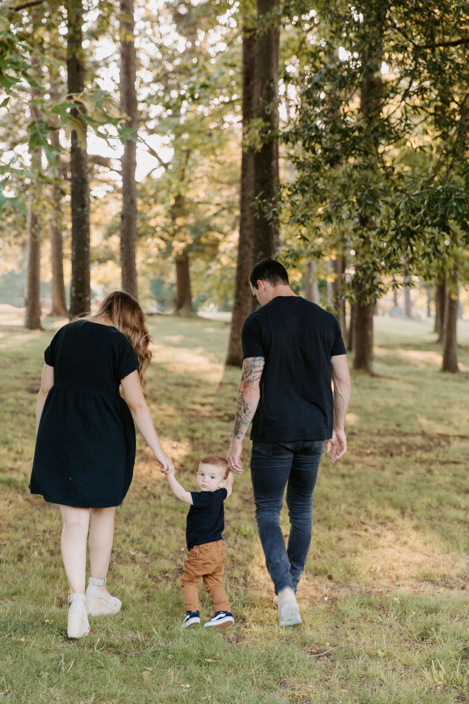 Family walking together through a scenic wooded park during golden hour.