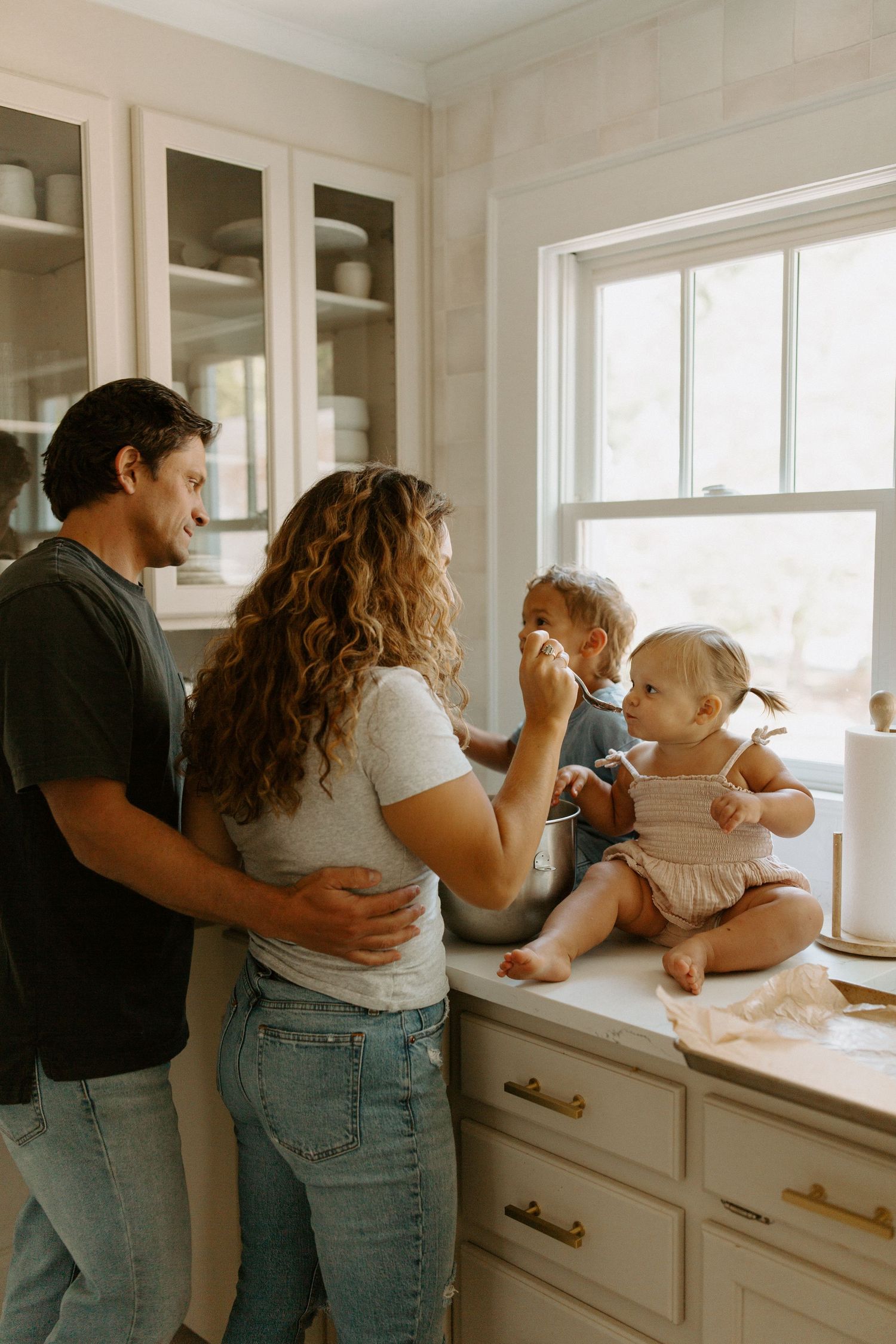 Family moment in a bright kitchen with white cabinets and natural window light.
