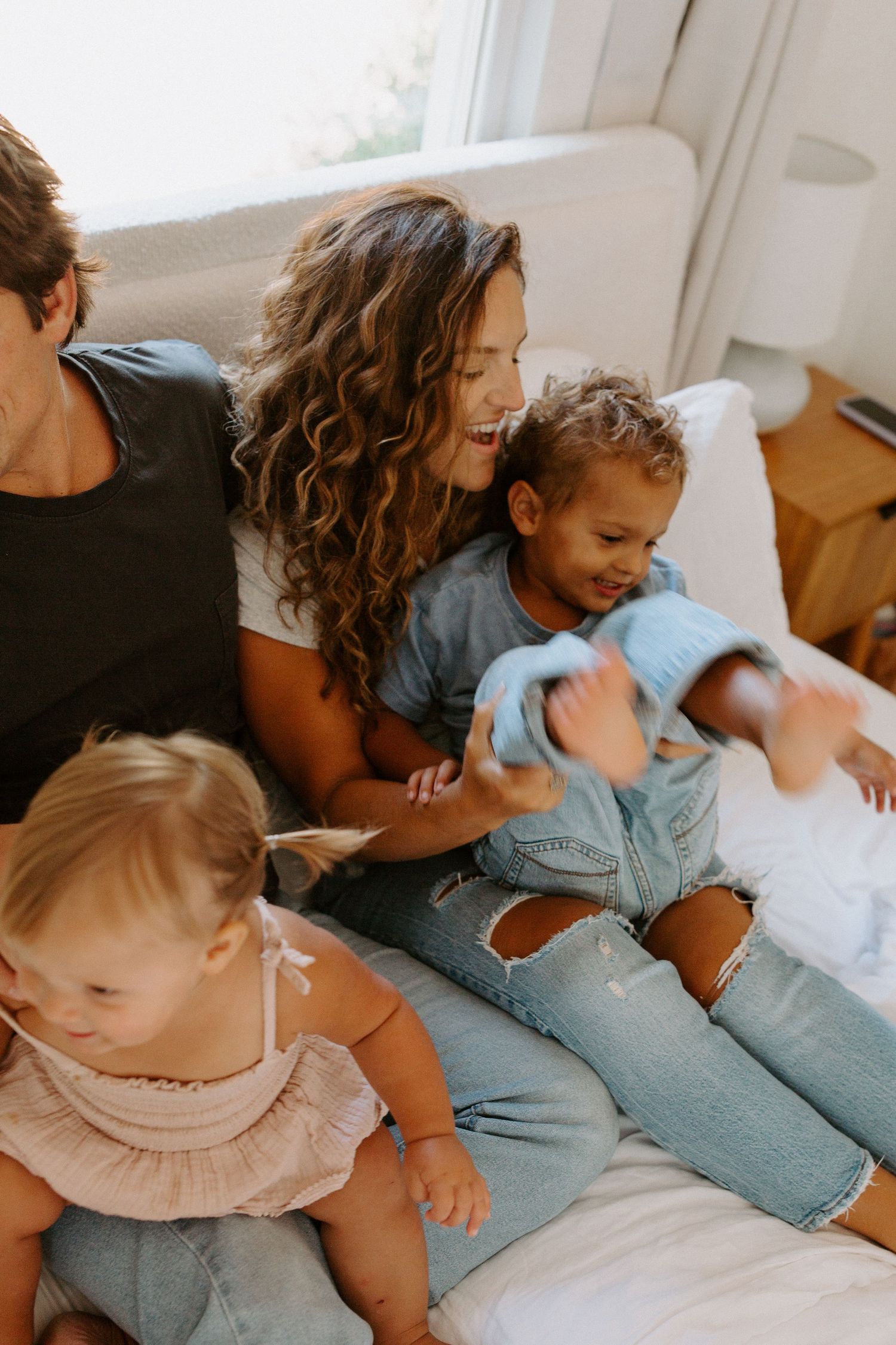 Casual lifestyle photos of family members in denim relaxing together on white bedding.