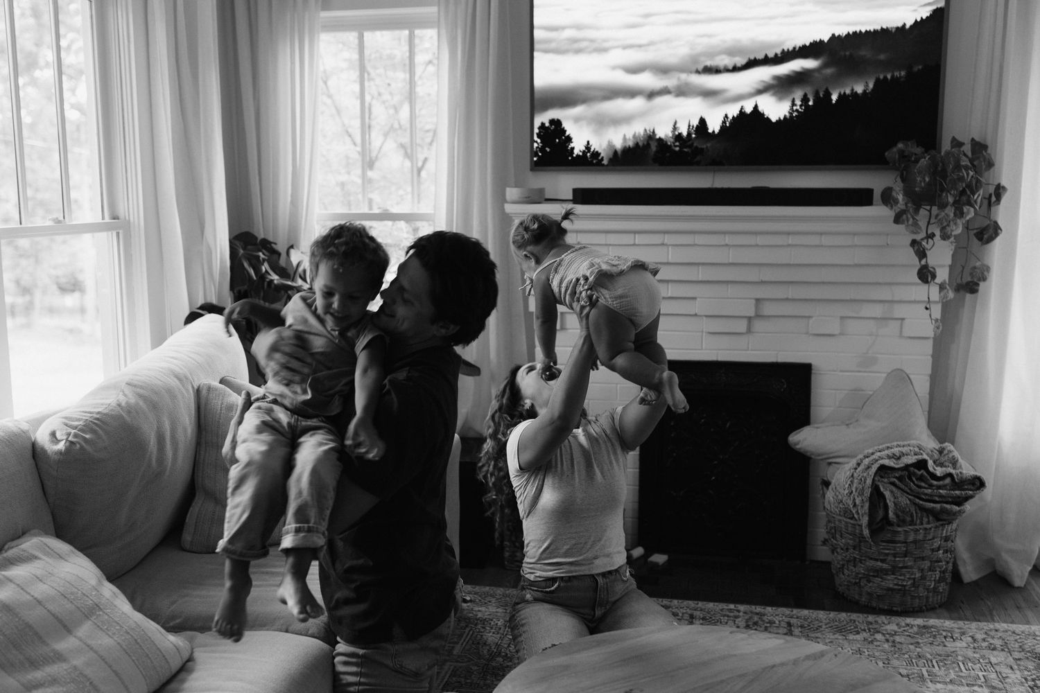 Black and white photo sequence of playful interaction on living room couch with landscape art above.