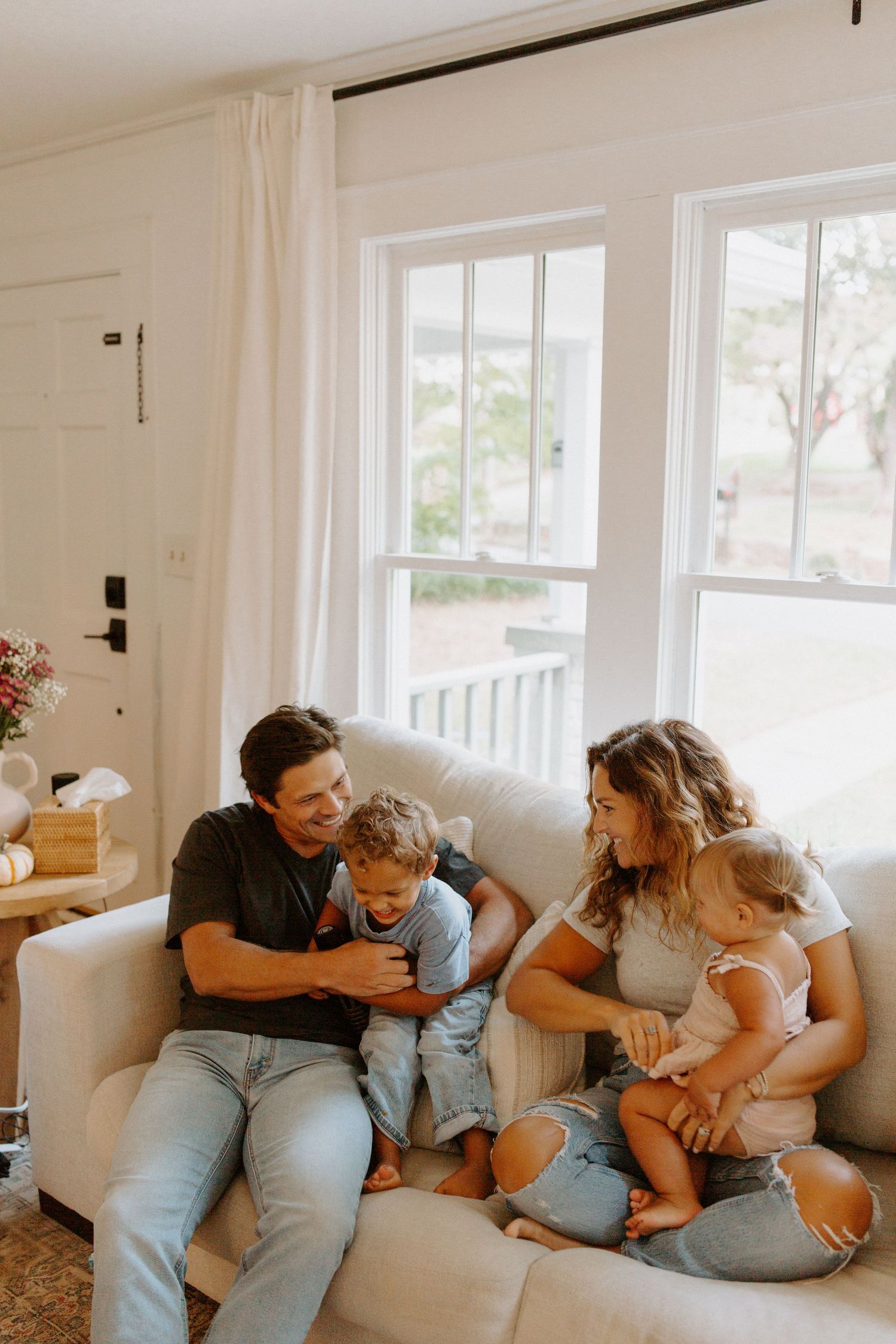 Natural light illuminates family cuddle time on white sectional sofa.