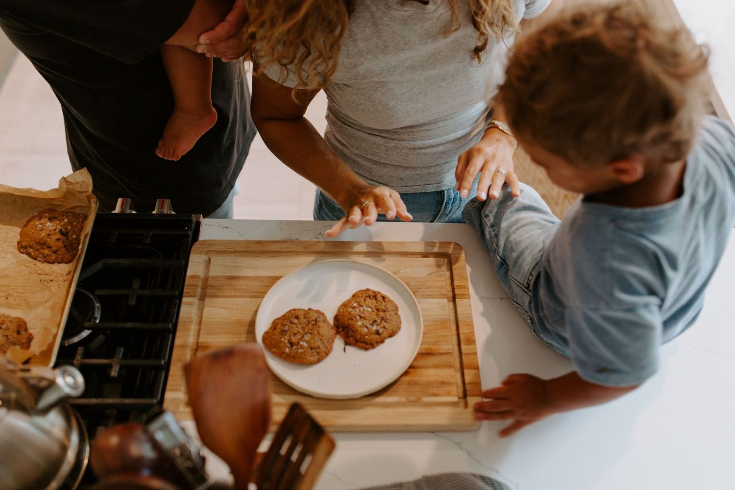 Multiple people gathered around a kitchen counter sharing freshly baked cookies.
