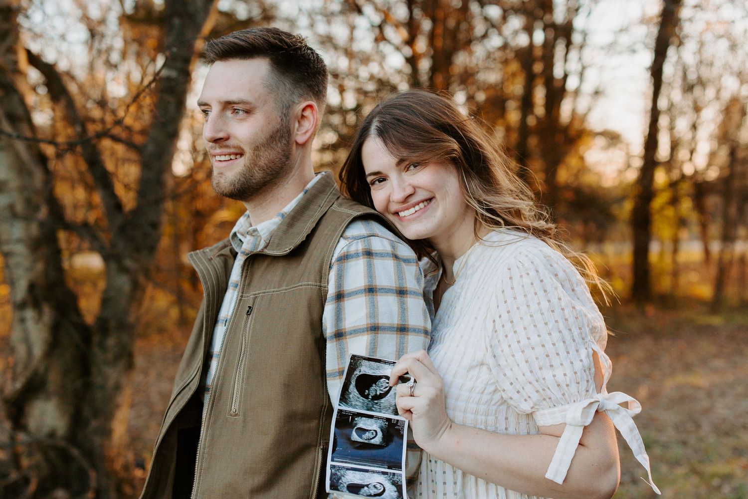 Couple walking through autumn woods holding vintage camera.