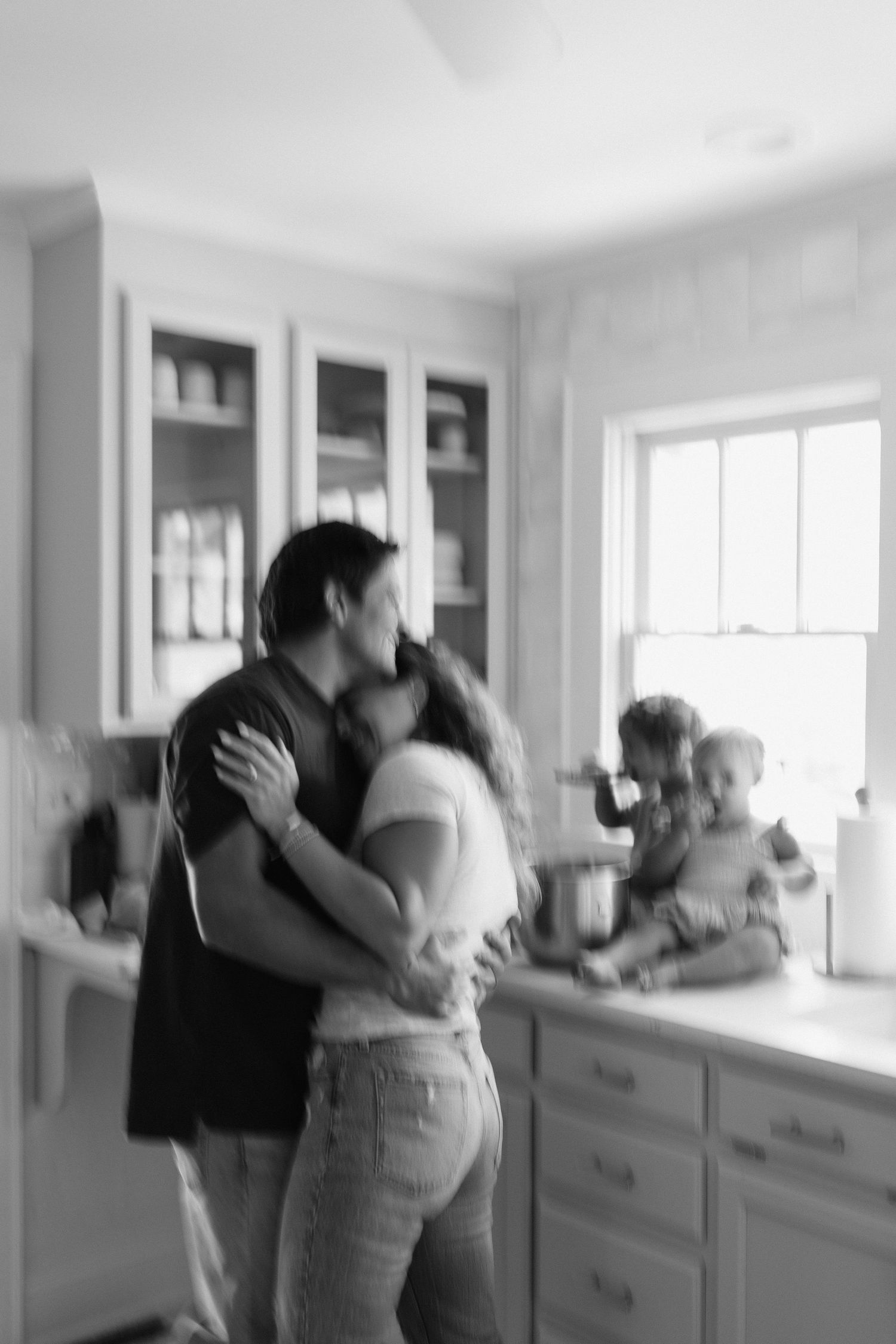 Family sharing playful moments together in a bright white kitchen while baking.
