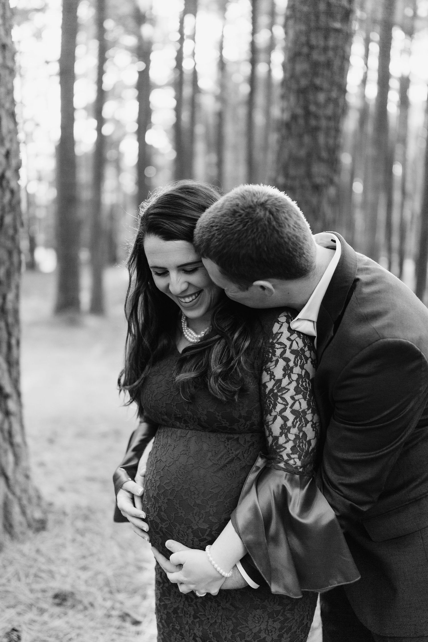 Joyful couple sharing intimate moment among pine trees.