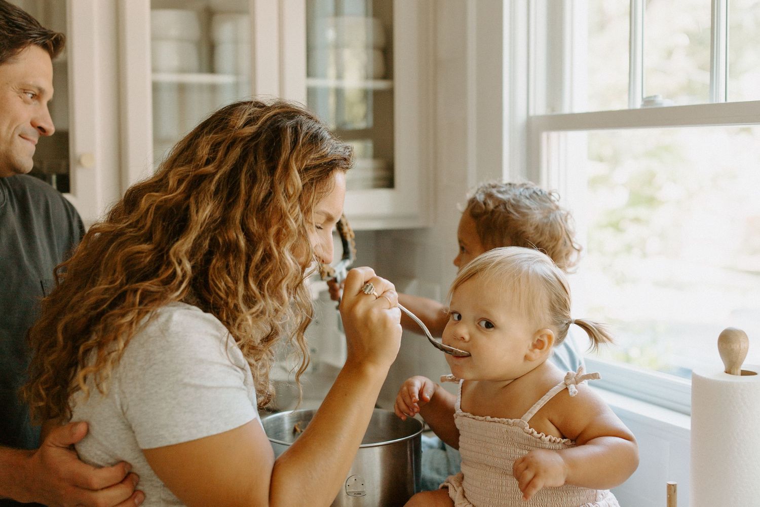 Family sharing a sweet baking moment together in a sun-lit kitchen.