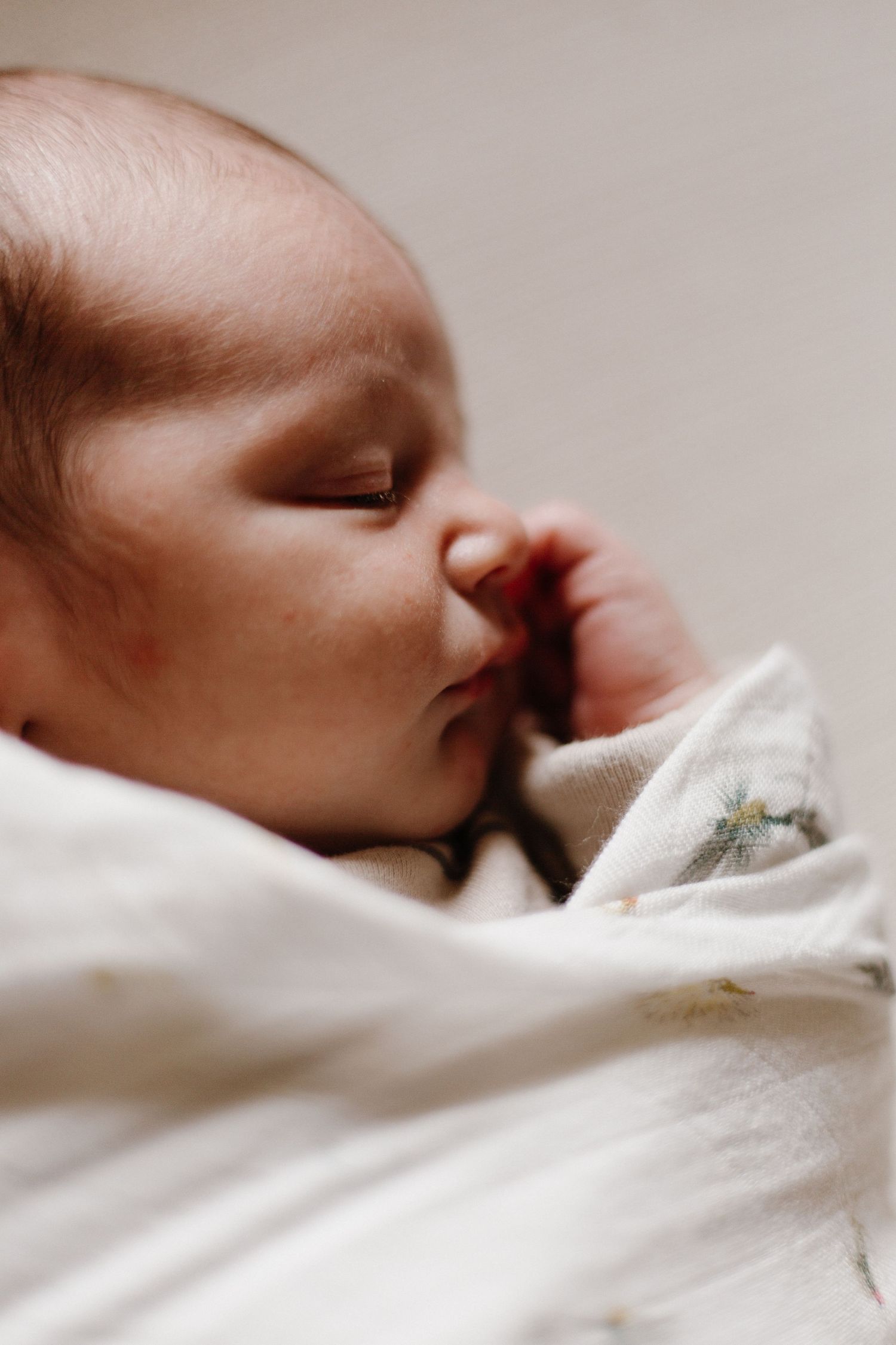 Peaceful sleeping newborn nestled in soft white bedding.