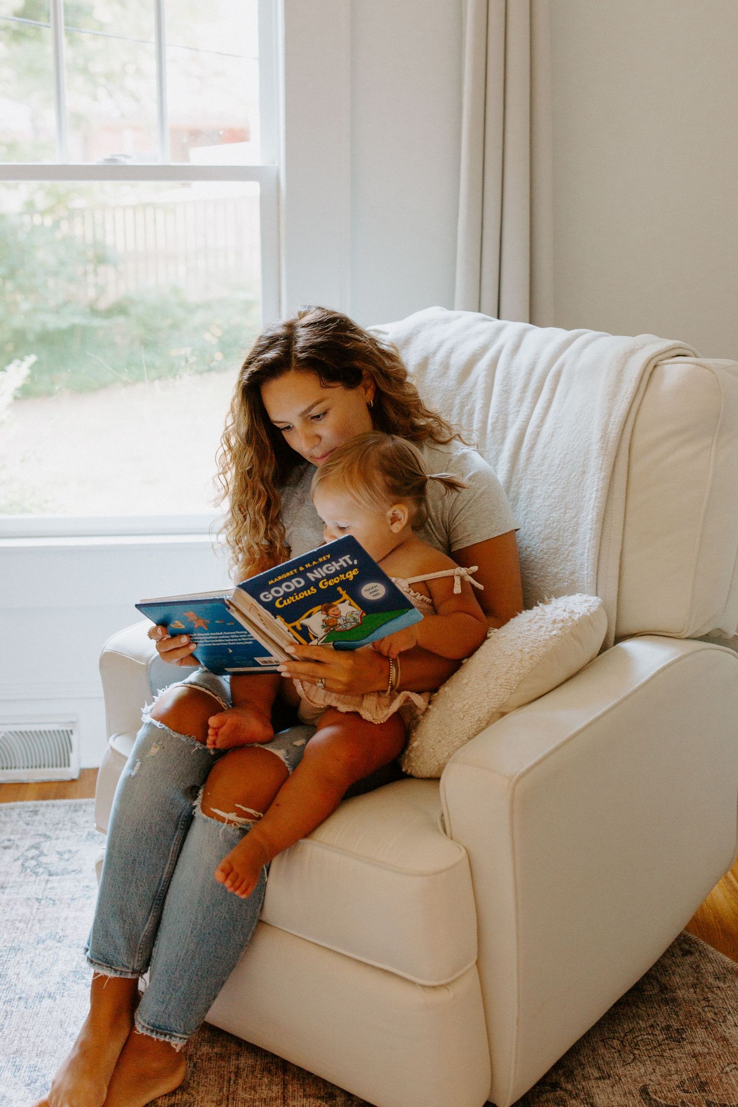 A cozy reading session on a white sofa in a naturally lit living room.