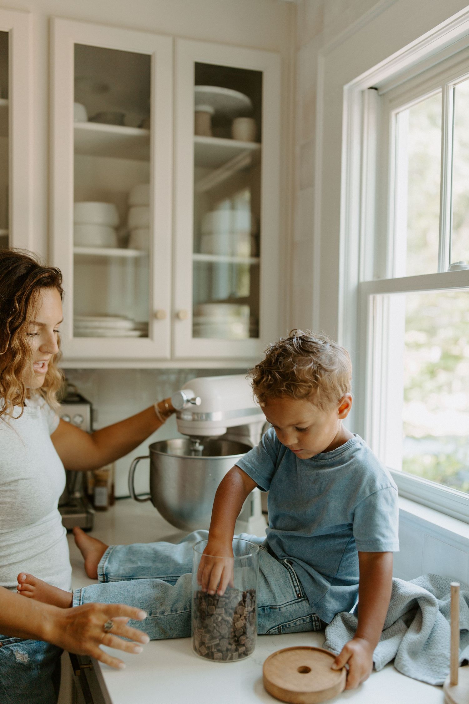 A casual kitchen scene with natural light streaming through white cabinet windows.