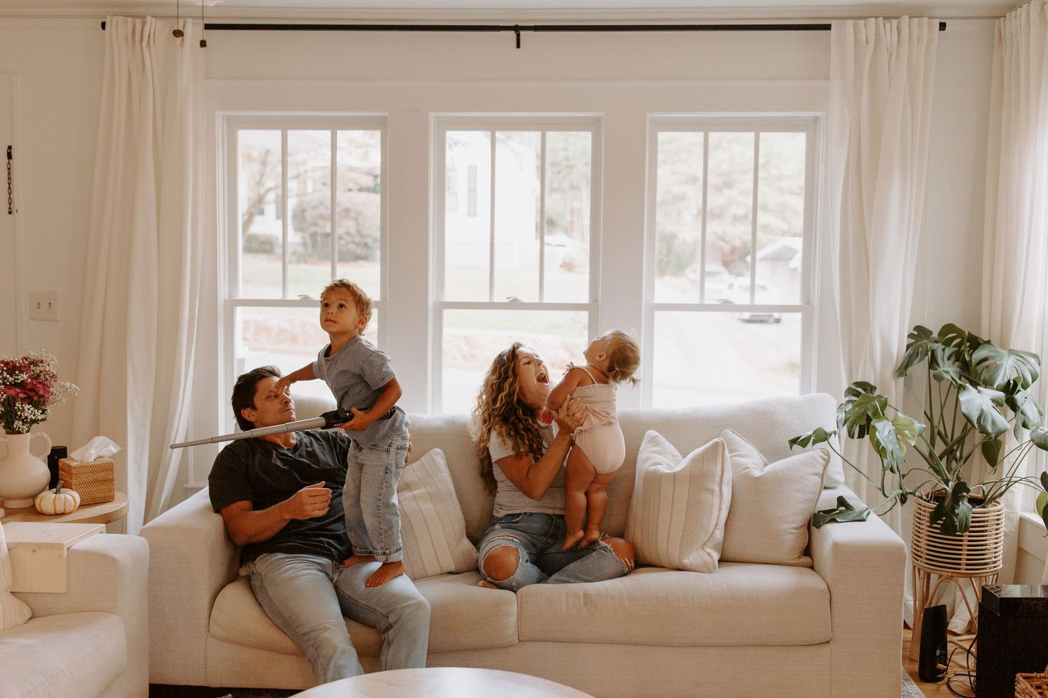 Candid family interaction captured in a bright, airy living space with white decor.