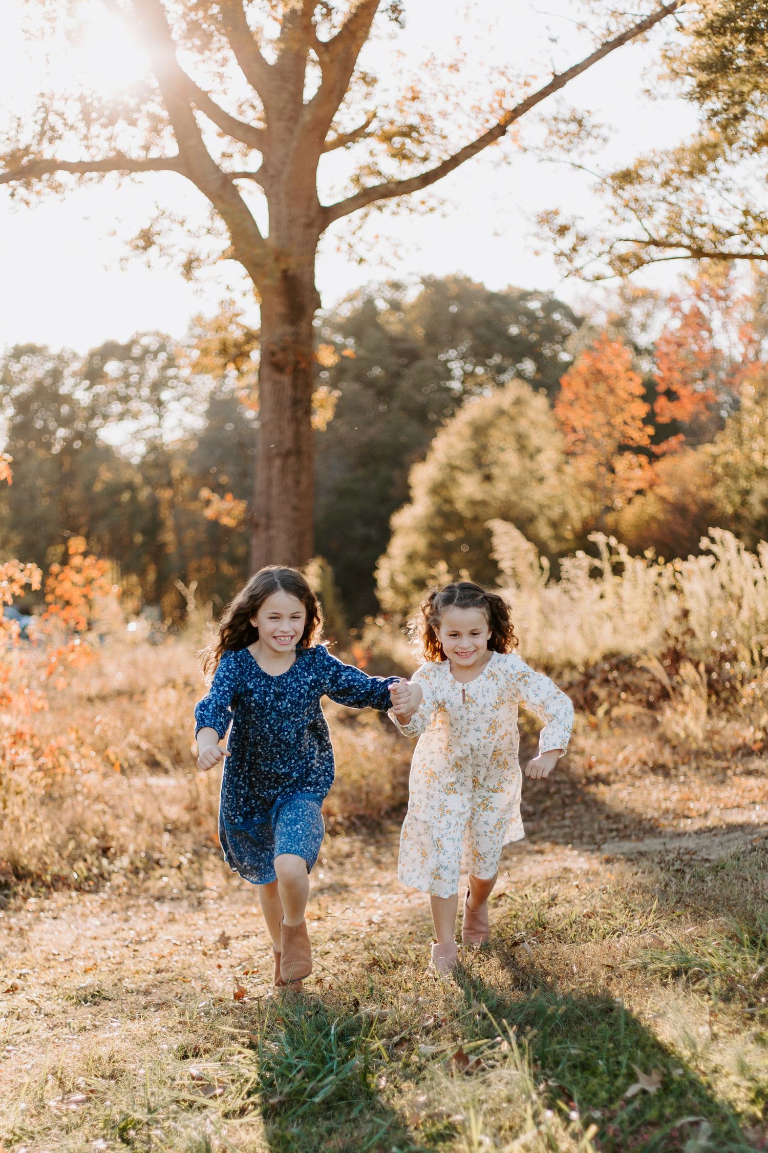 Two children running through a sunlit field during golden hour.