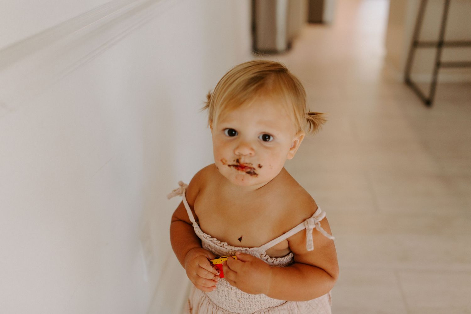 A small toddler in light clothing explores a bright modern kitchen space.
