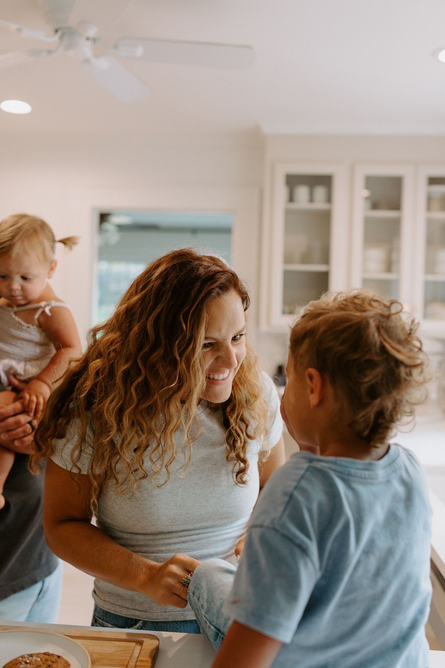 A joyful moment shared in a sunlit kitchen with white cabinets.