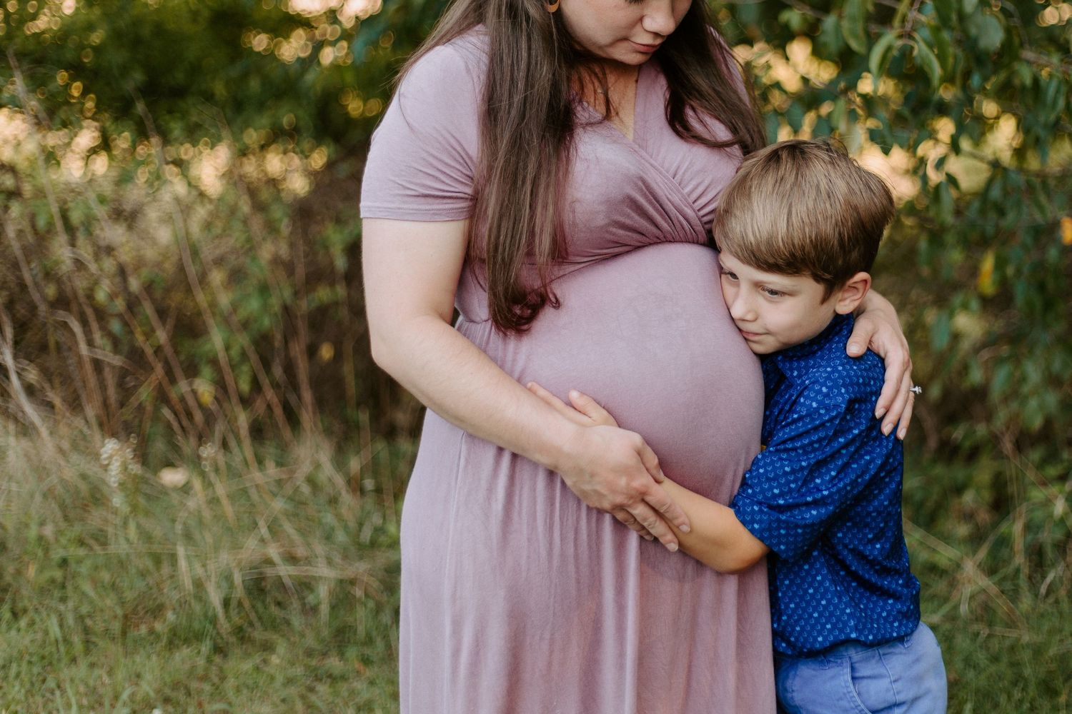 A tender moment captured in a garden setting with a mauve dress and blue shirt creating a warm family scene.