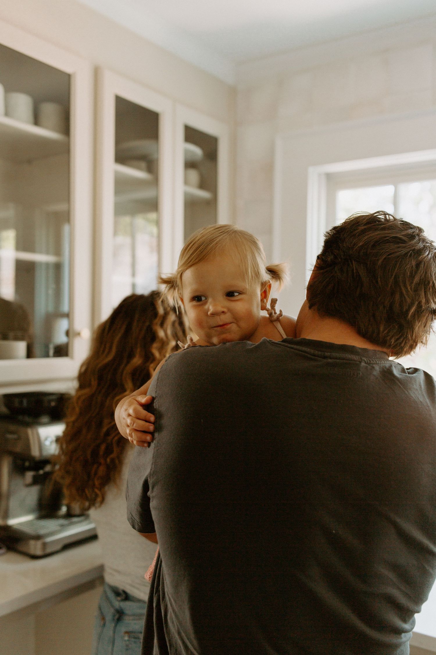 Candid moment in a bright kitchen with white cabinets and natural lighting.