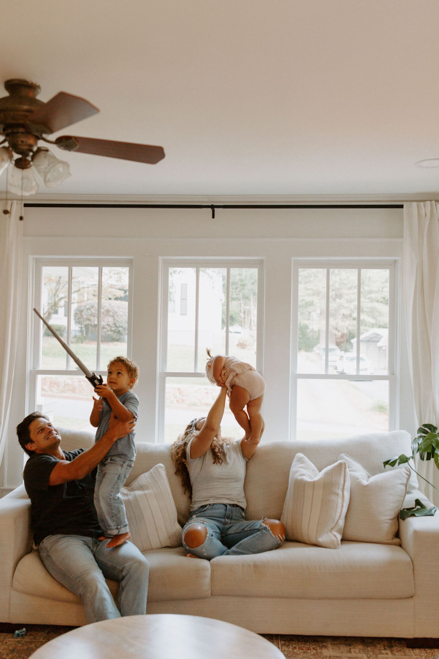 Playful family photoshoot sequence showing fun interactions on white couch.