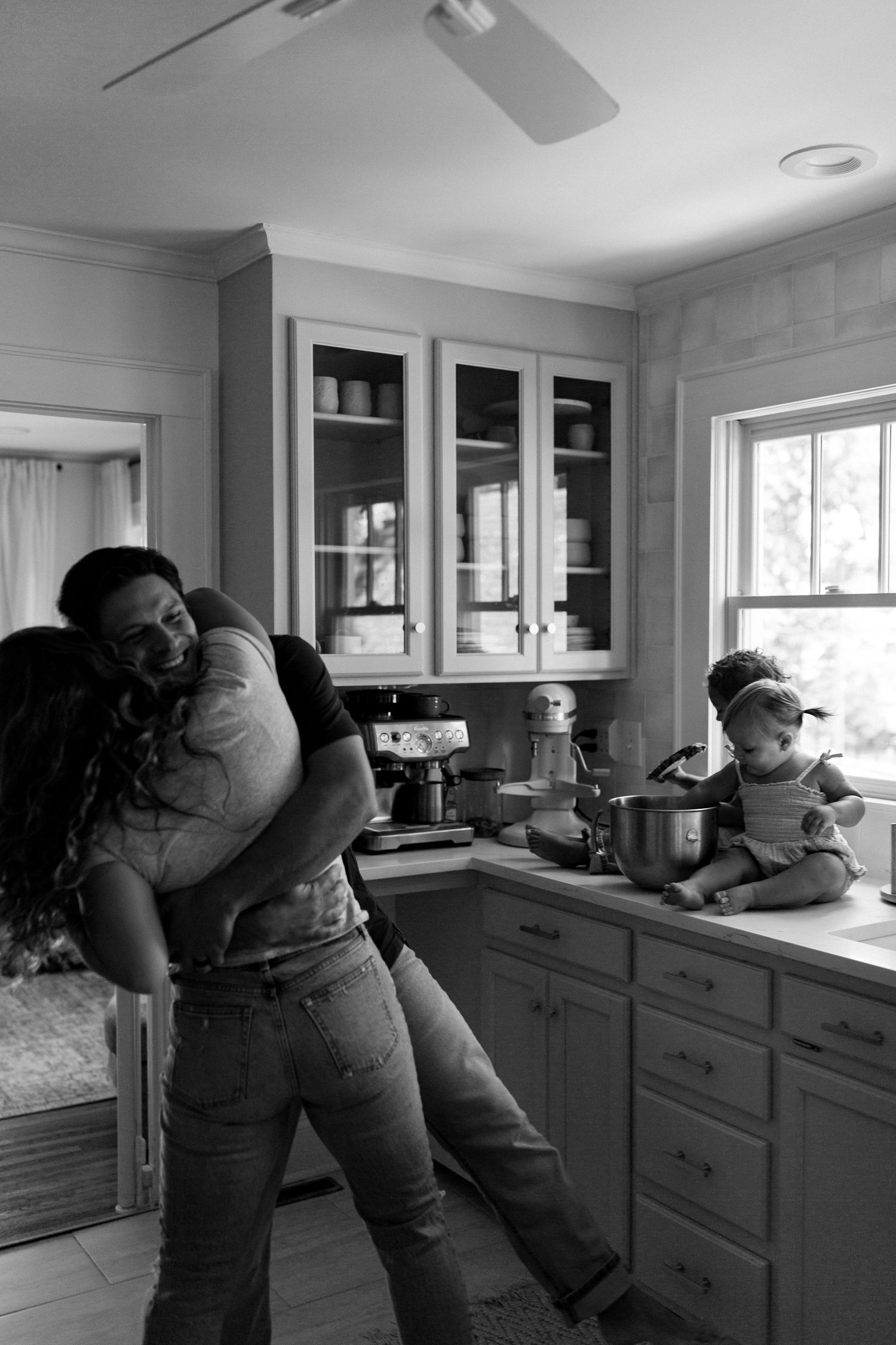 Series of intimate family moments captured in black and white in a bright kitchen space.