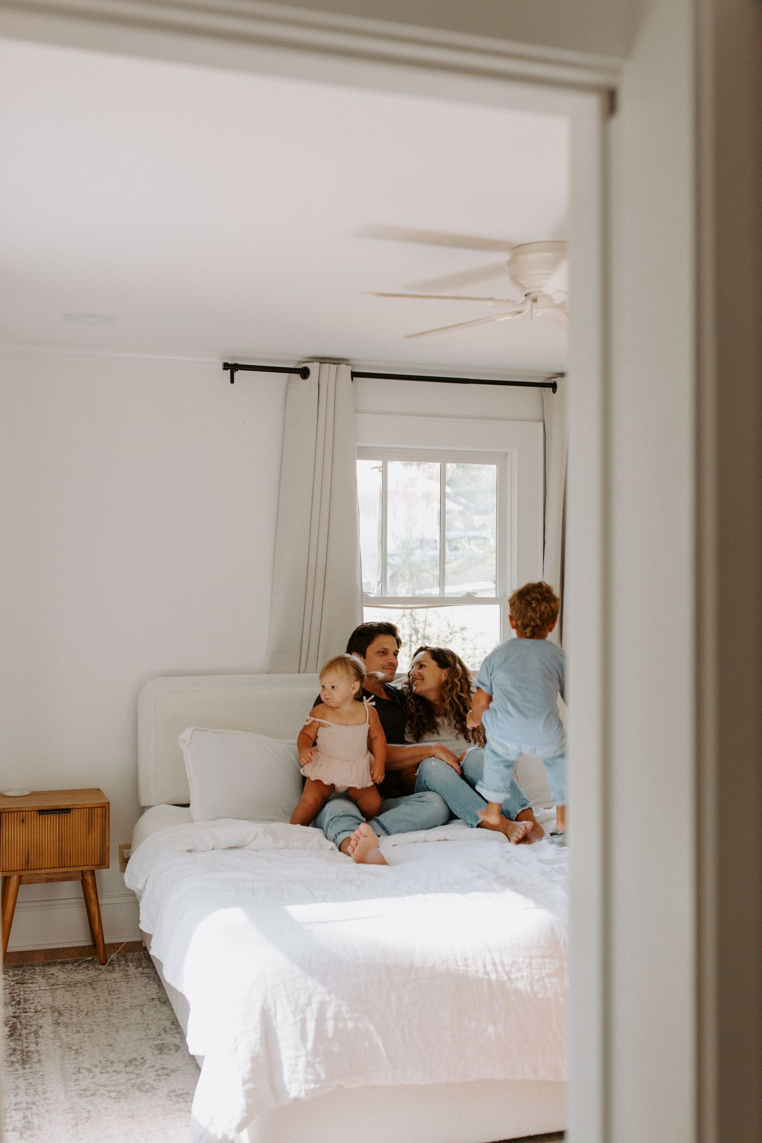 Natural light streams into bedroom as family shares tender moments together.