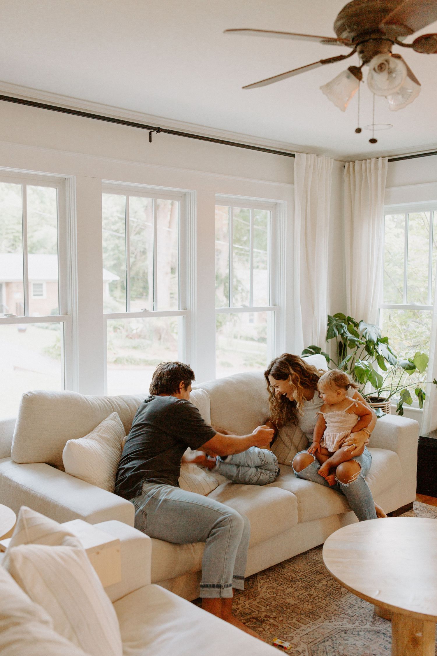 People enjoying playful moments together on a comfortable sectional sofa in a modern white living room.