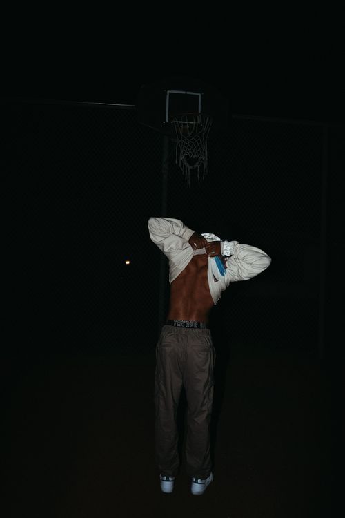 Guy lifting up the back of his shirt on a basketball court.
