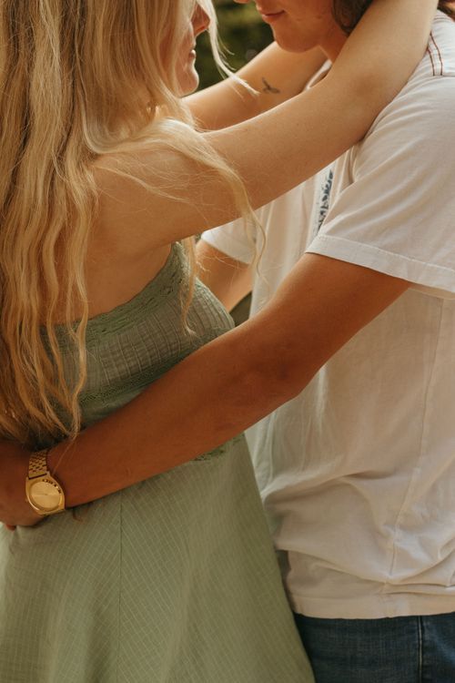 Couple in casual summer attire sharing tender moment outdoors.