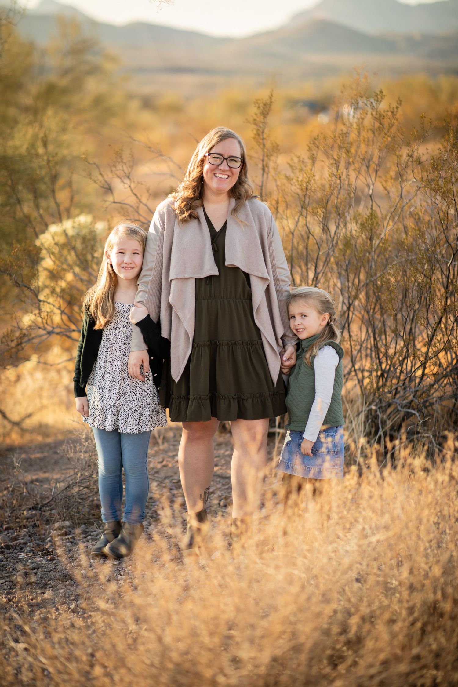 Family enjoying golden hour in desert landscape with tall dry grass and mountains in background at Lost Dutchman state park.