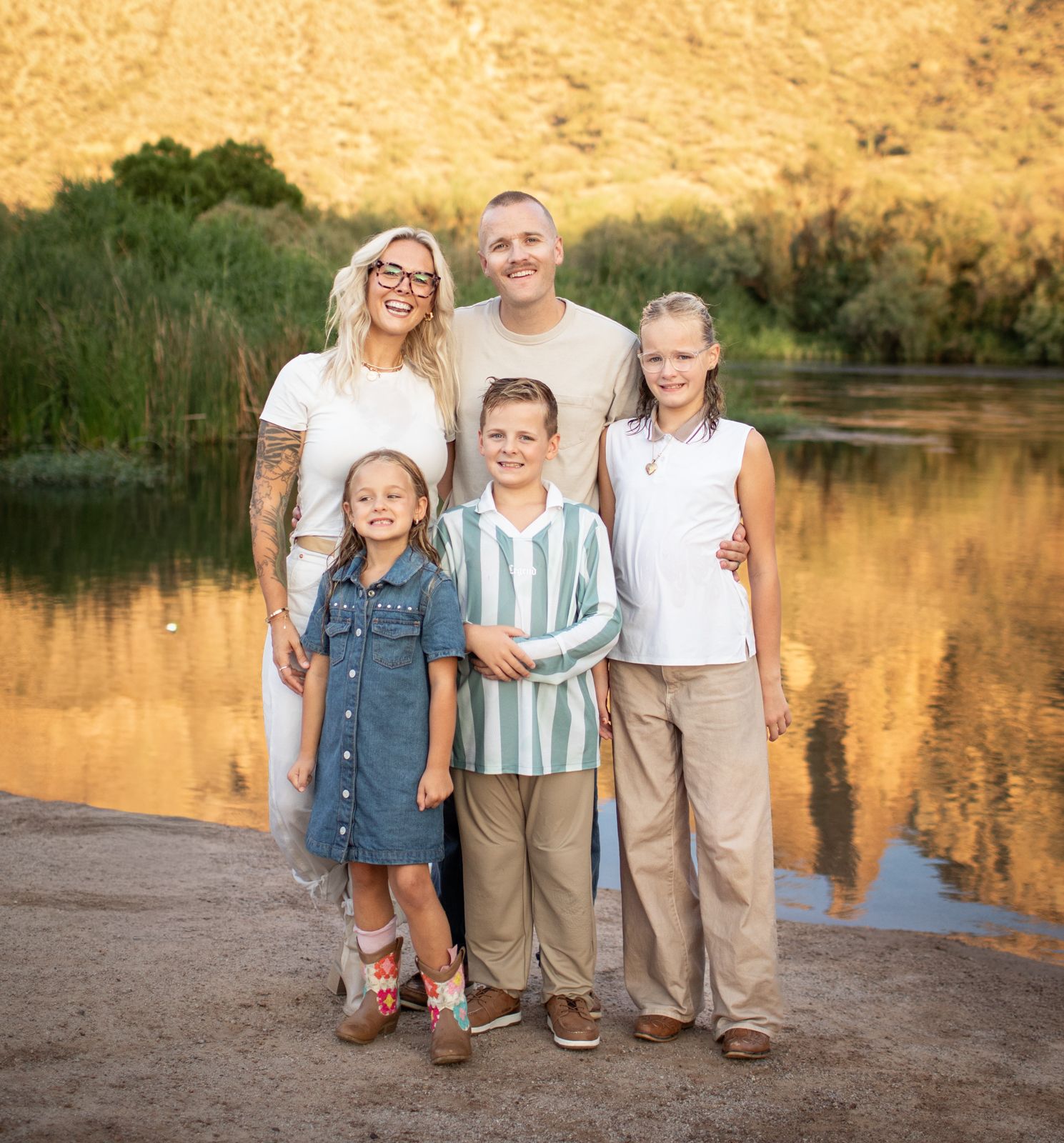 Family portrait at sunset by a lake with golden cliffs reflecting in calm waters at Water Users recreational area.