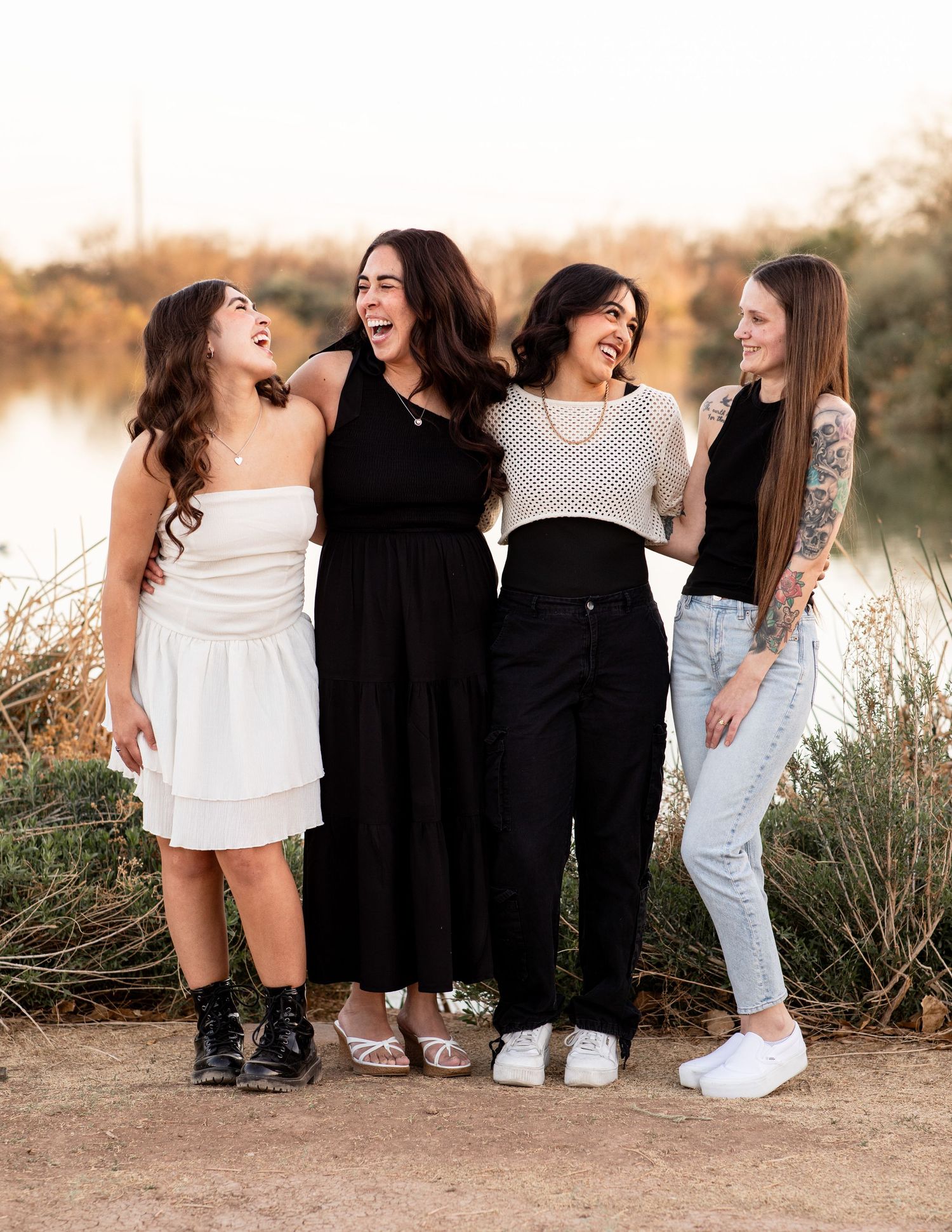A group of friends in casual attire laughing and walking together during golden hour in a desert landscape.