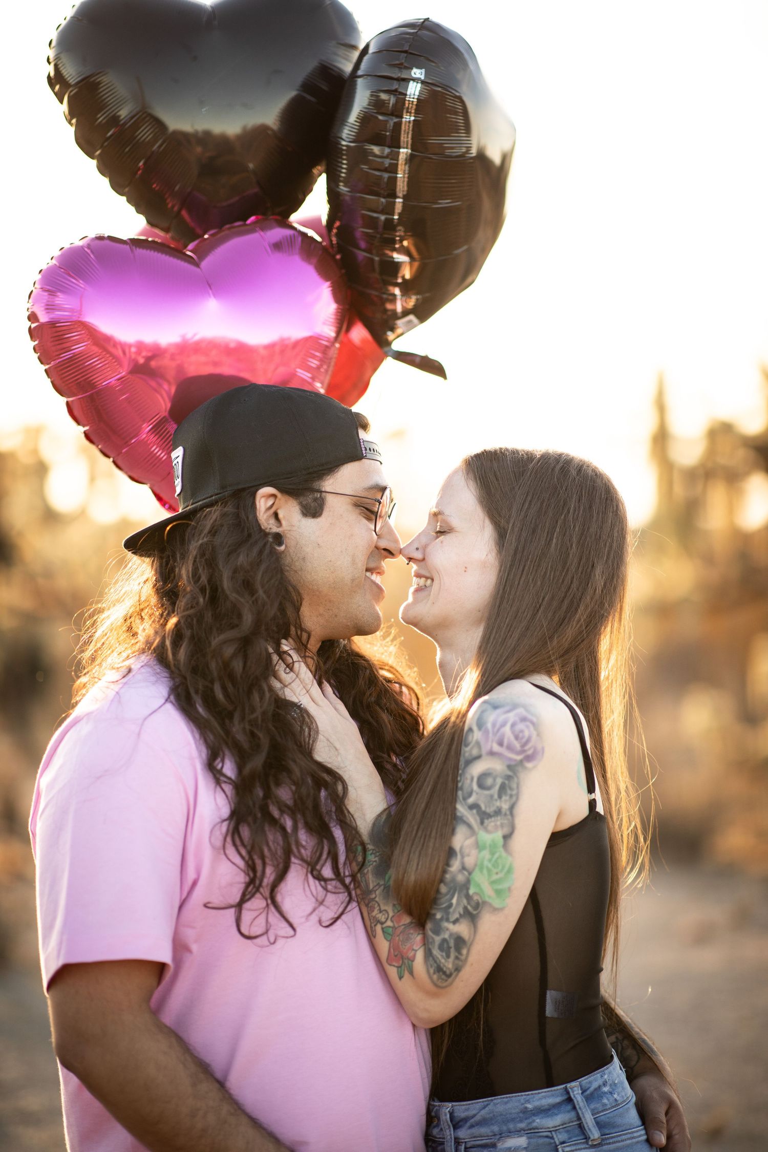 A romantic couple shares intimate moments at sunset in a desert landscape, with warm golden lighting at Desert Arroyo Park in Mesa, Arizona.