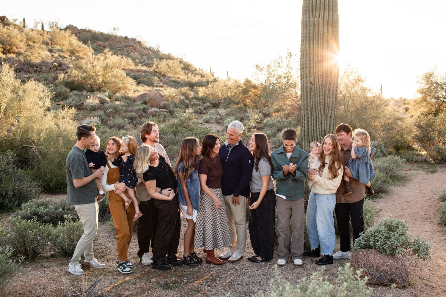 Group of people sitting together in a desert landscape with saguaro cacti and mountains during golden hour sunset in Usery Pass in Mesa, AZ