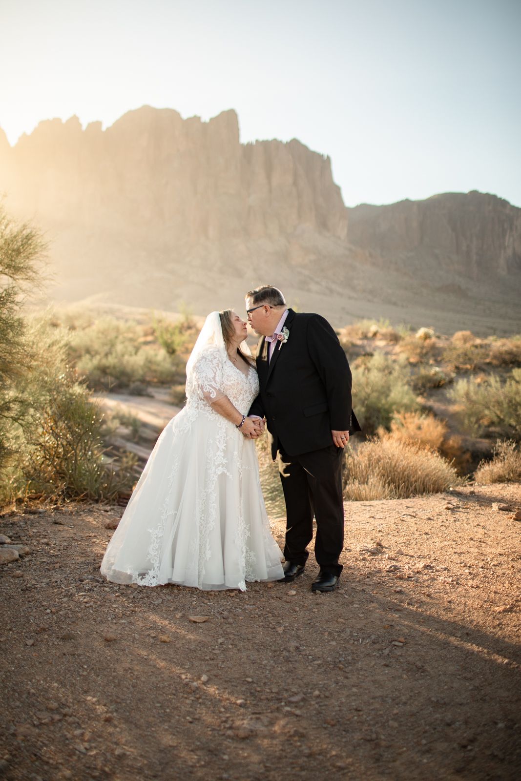 Desert wedding photos at sunset with dramatic mountain backdrop in golden light.