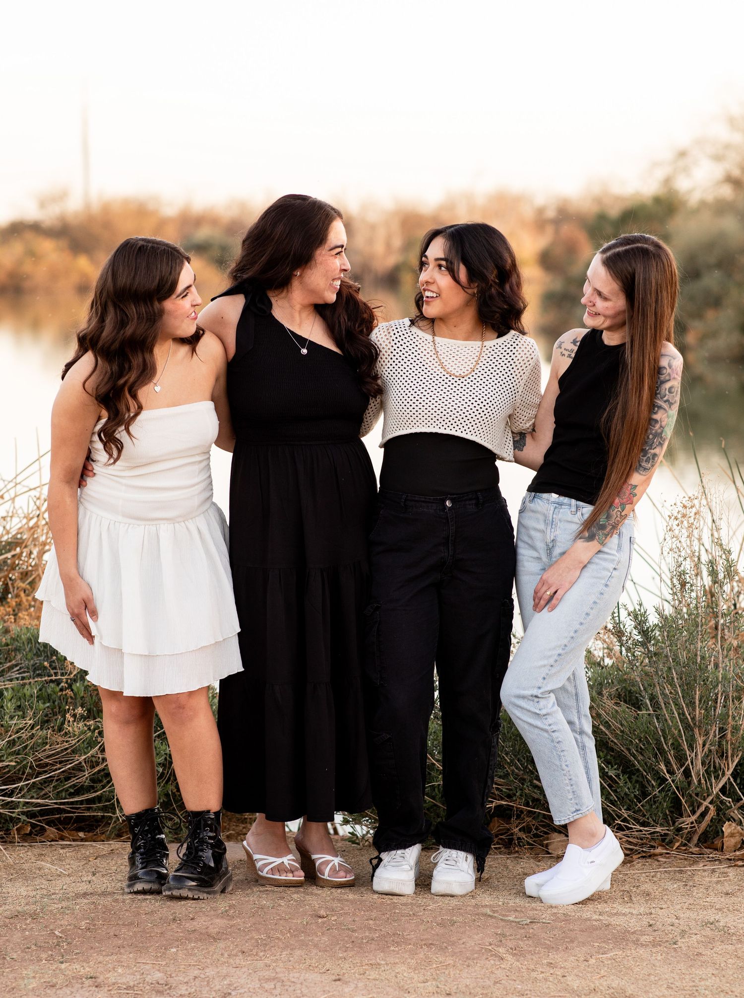A group of friends in casual outfits sitting together outdoors during golden hour at sunset.