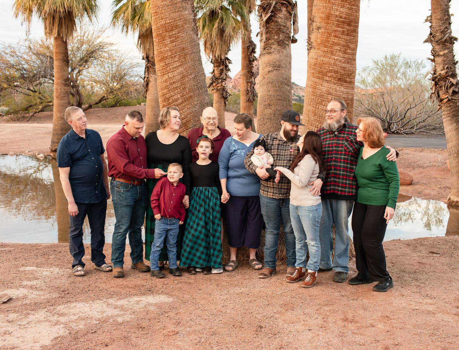 A group of people stand together in a line against a backdrop of palm trees in a desert landscape in Papago Park in Phoenix, AZ.