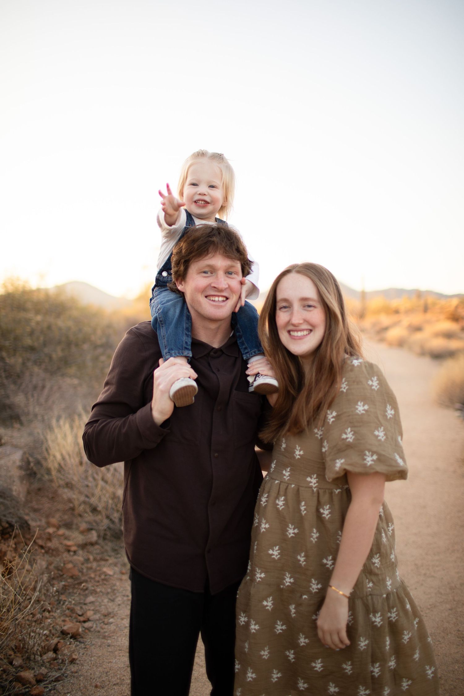 Family enjoying playful moments together on a desert trail at sunset.