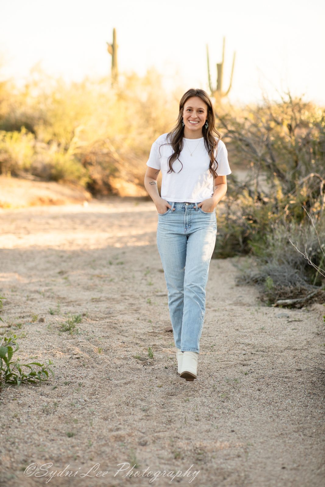 Casual outfit of white t-shirt and light jeans shown walking in desert landscape.