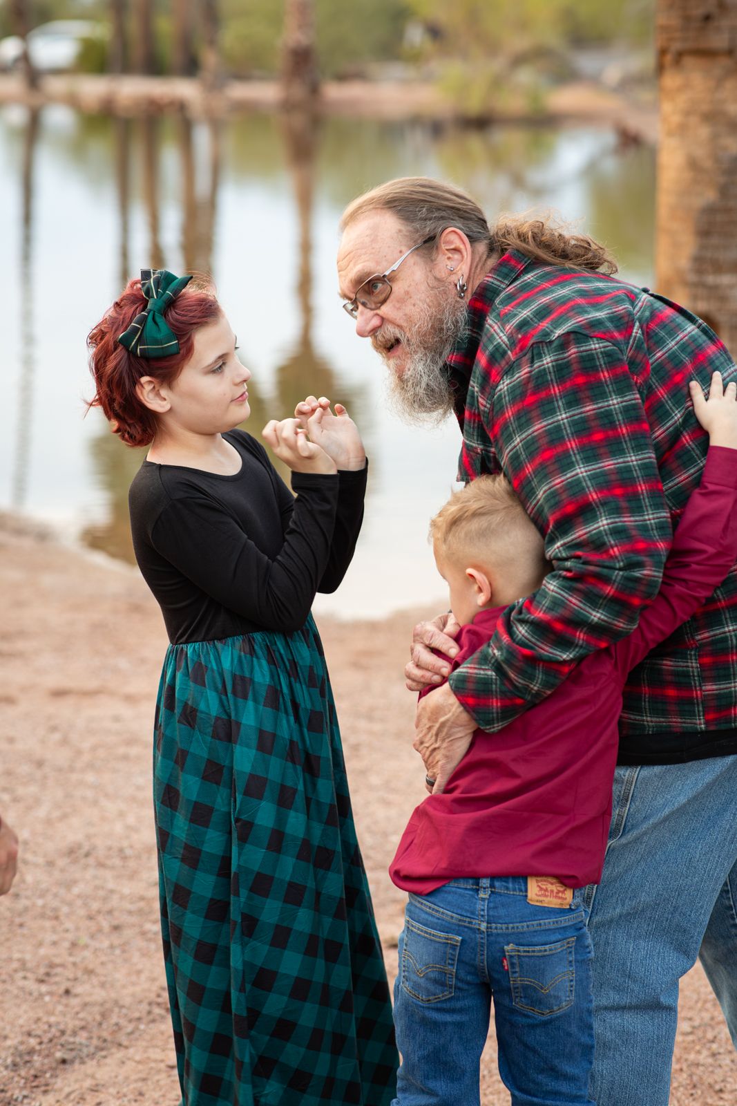 Family members in plaid shirts share playful interactions outdoors against a natural background in Papago Park in Phoenix, AZ.