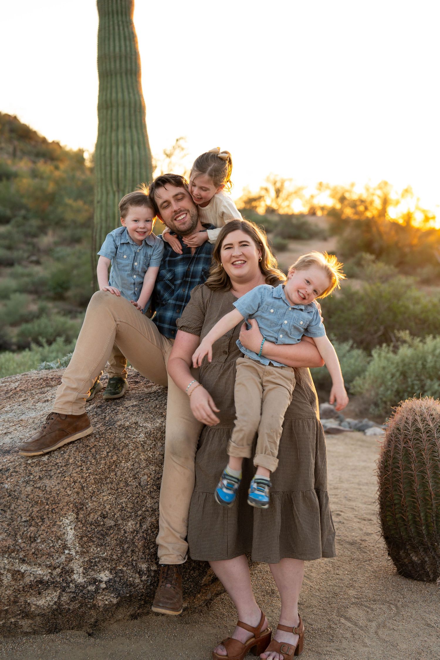 A family poses together in the desert at sunset with saguaro cacti in the background at Usery Pass in Mesa, Arizona.