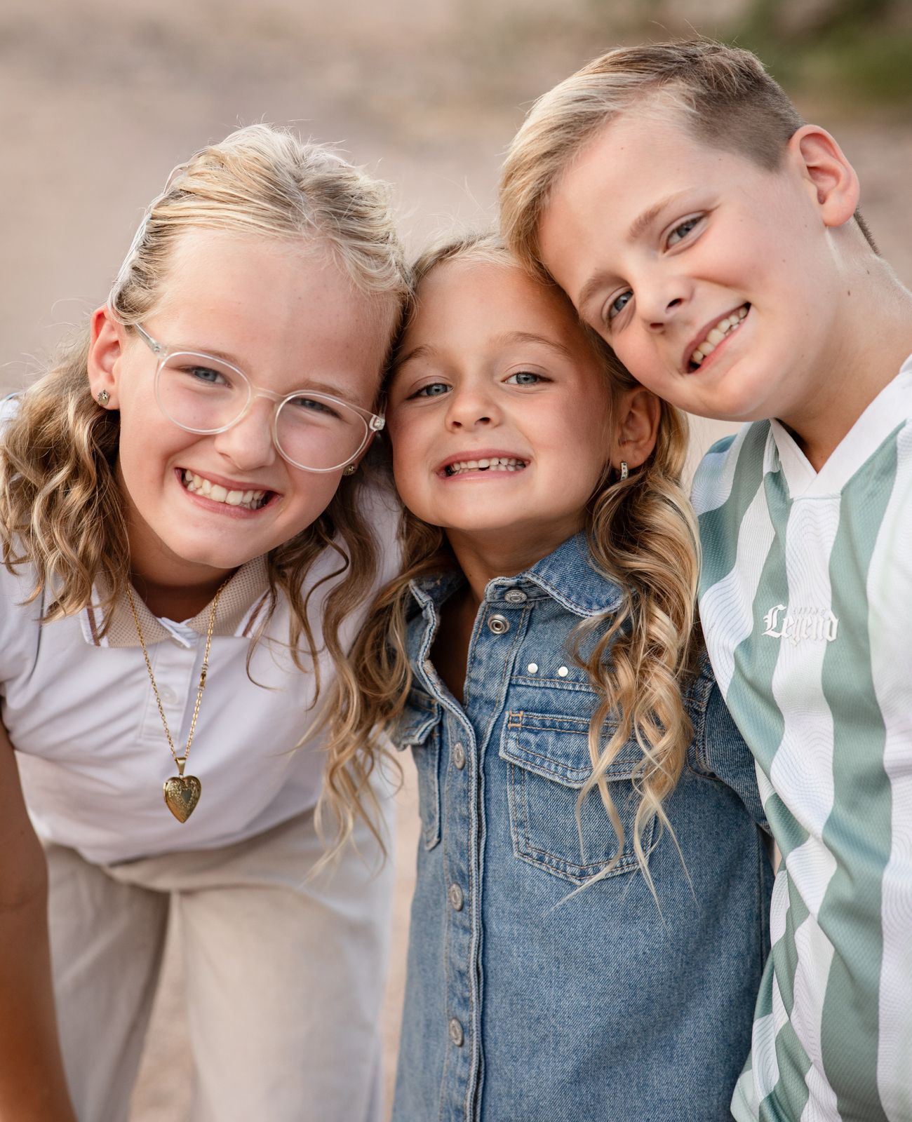 Three children pose close together with playful smiles against a light background at Water Users recreational area.