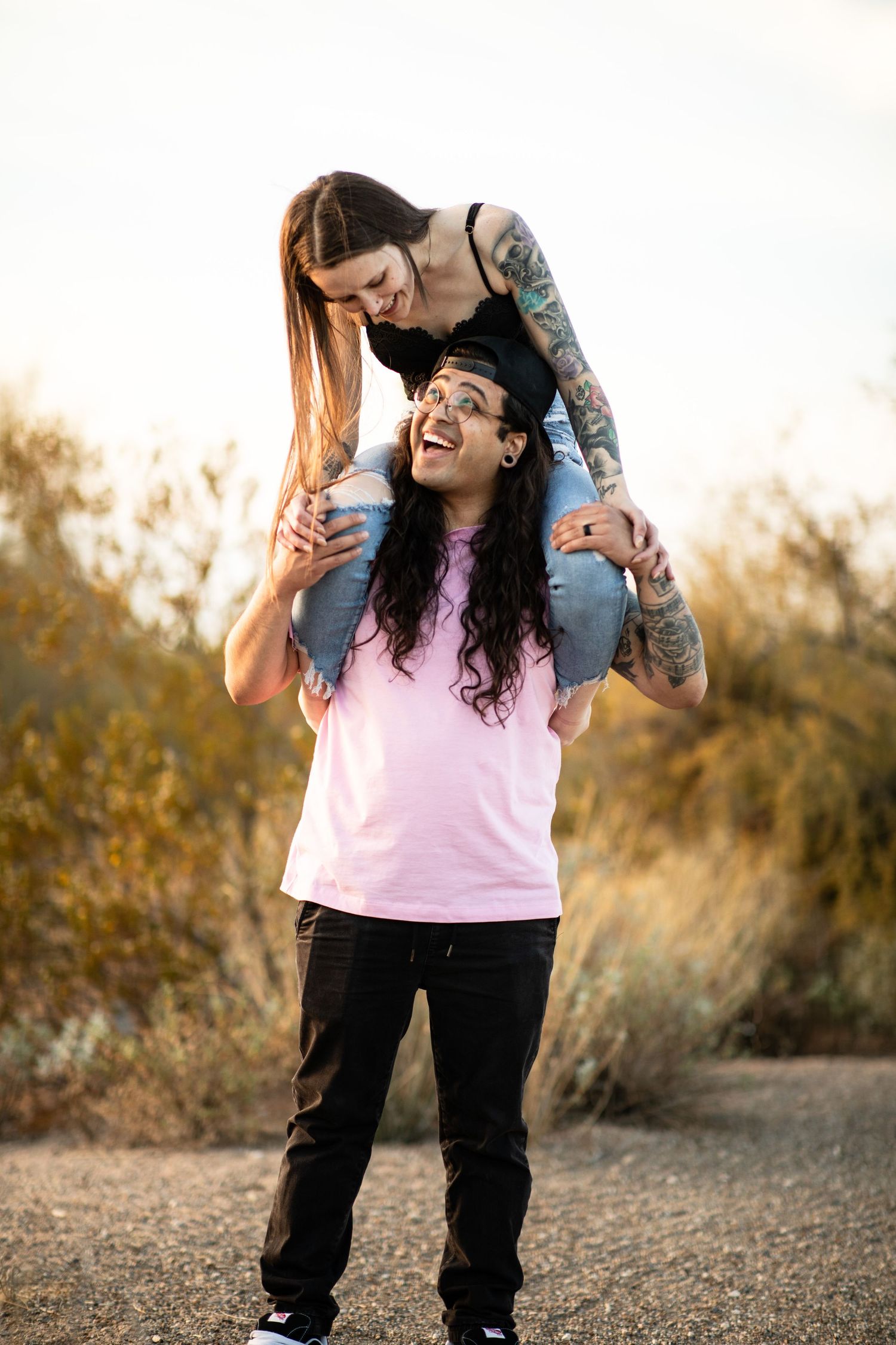 Two people share joyful laughter while posing together outdoors at sunset at Desert Arroyo Park in Mesa, Arizona.