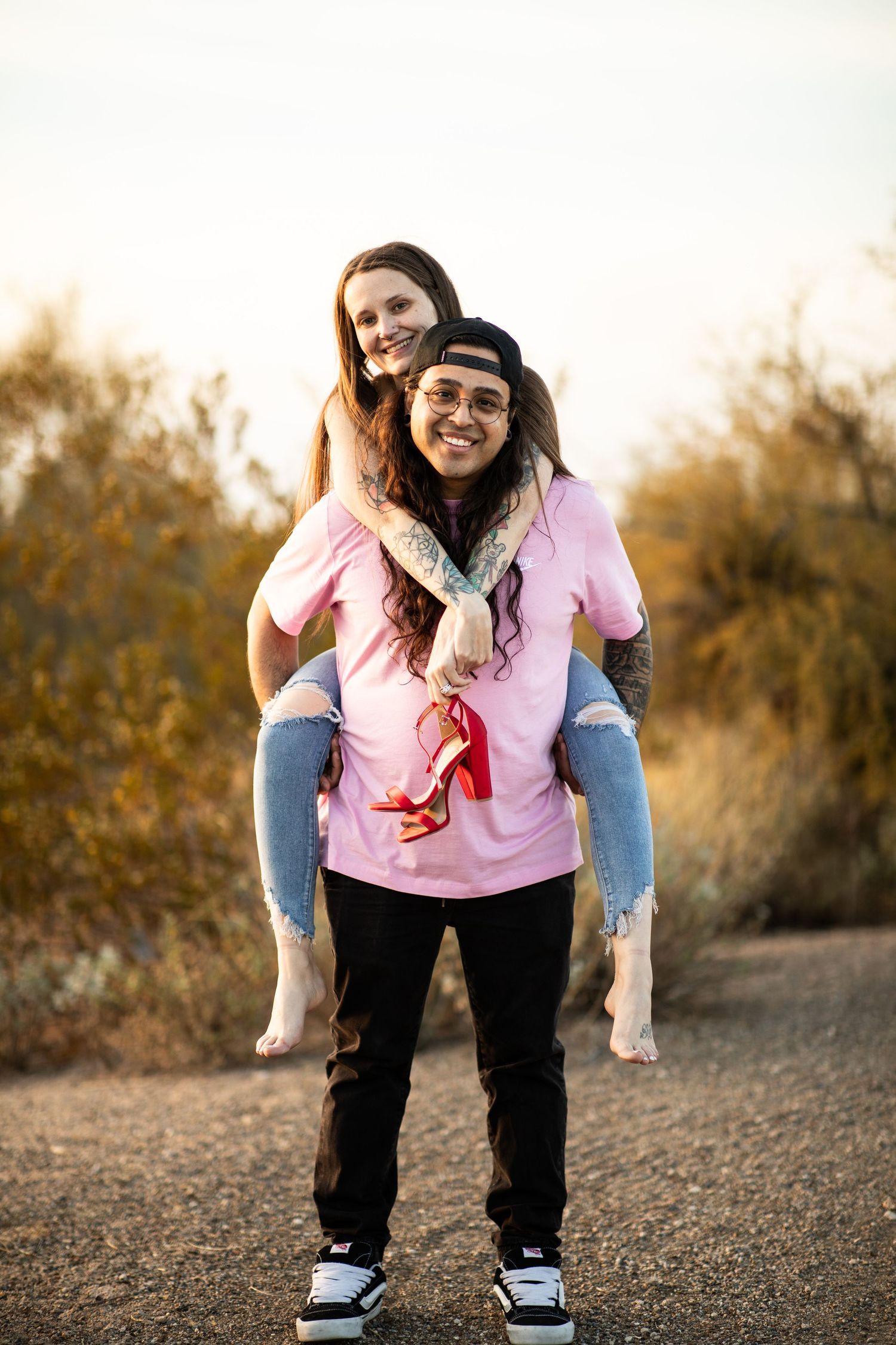 A playful piggyback ride captured at sunset with desert brush in the background at Desert Arroyo Park in Mesa, Arizona.