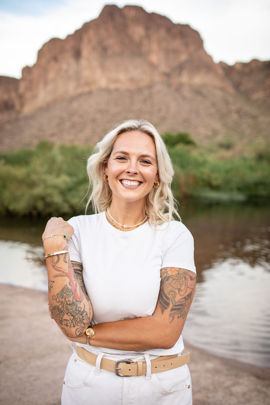 A joyful portrait in white attire against a scenic desert mountain and lake backdrop at Water Users recreational area.