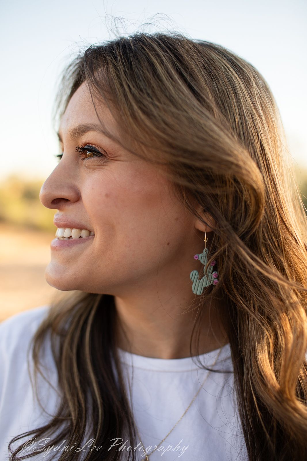 Side profile portraits showing cactus earrings and natural hair styling against desert backdrop.