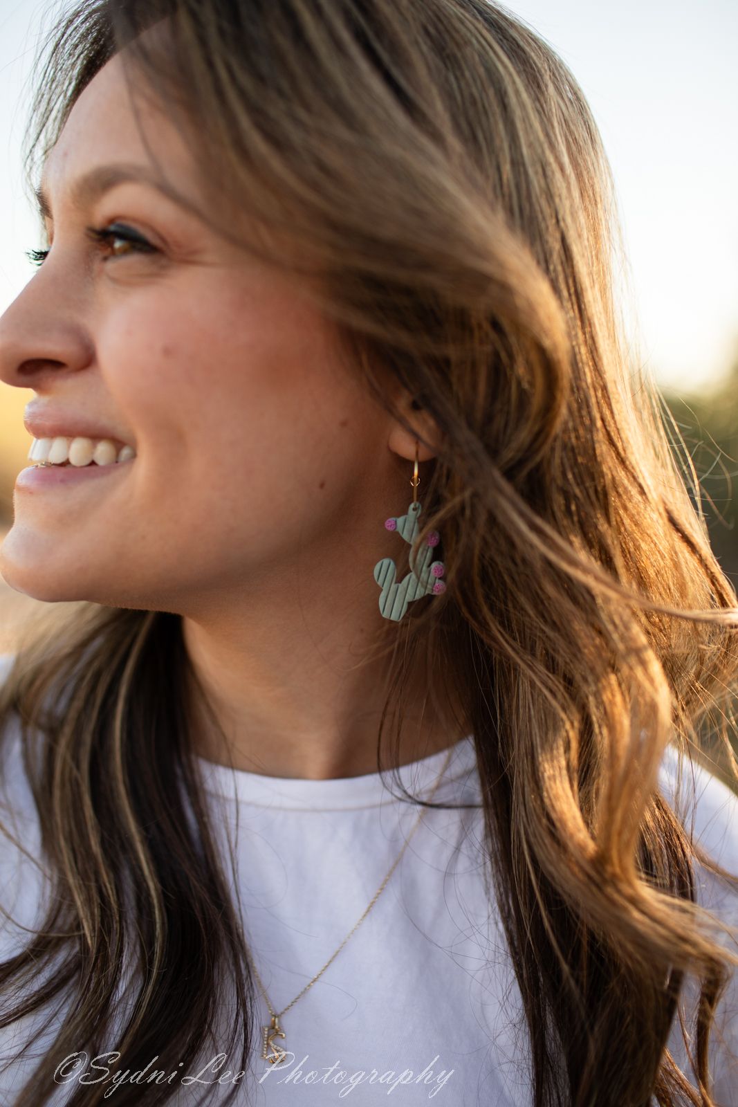 Profile shots showing cactus-shaped earrings and natural hair styling with golden hour desert lighting.