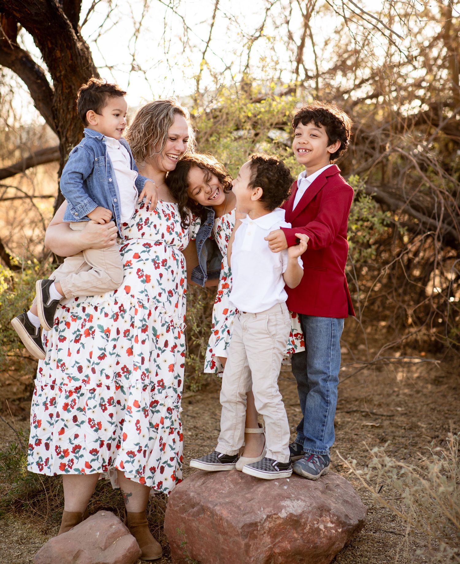 Children play and laugh together on a large rock during an outdoor family photo session at sunset at The Riparian Preserve in Gilbert, AZ.