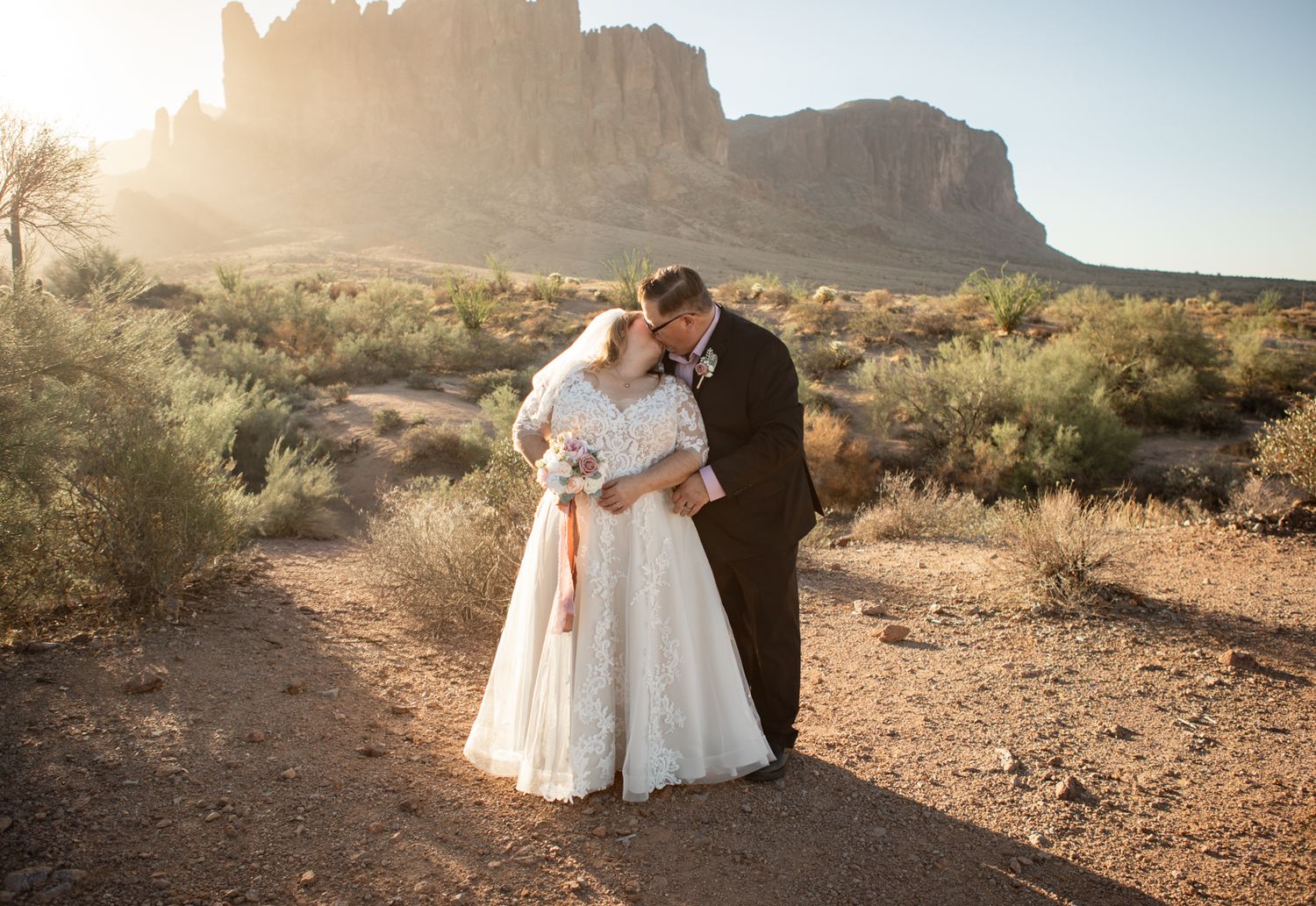 Wedding couple sharing an intimate moment on the treasure loop trail with the superstition mountain backdrop at sunset.